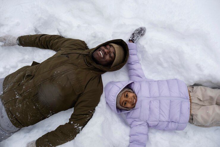 young-girl-making-snow-angels-with-her-father-winter_23-2149328424.jpg